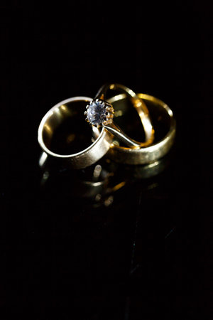 Gold wedding ring on black glass