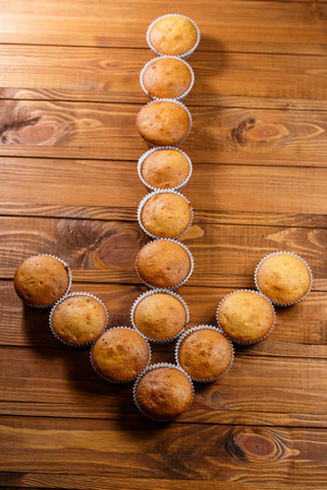 Homemade muffins in paper wrap on wooden boardの写真素材