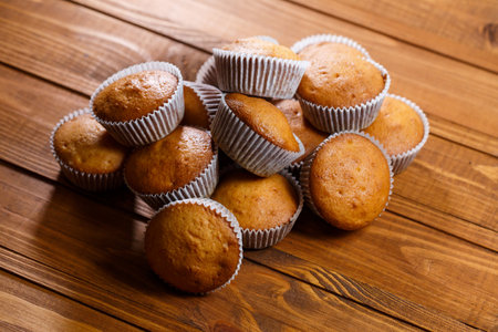 Homemade muffins in paper wrap on wooden boardの写真素材