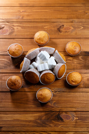 Homemade muffins in paper wrap with marshmallows on wooden boardの写真素材