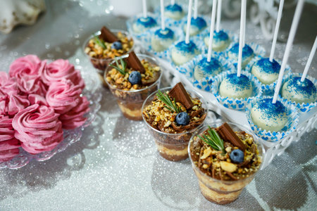 Beautifully decorated sweet buffet table on which cakes, muffins, marshmallows, pecans. Dessert table for a party, goodies for the wedding. Close up. Candy bar. A buffet for a weddingの写真素材