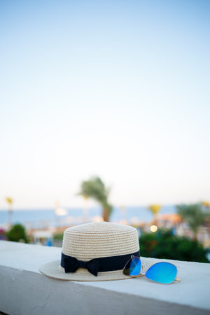 Women's summer hat and glasses lie on the terrace overlooking the seaの写真素材