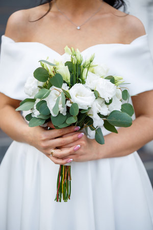 Hands of the bride close-up with a bouquet of fresh beautiful flowers. Attribute of the brideの写真素材