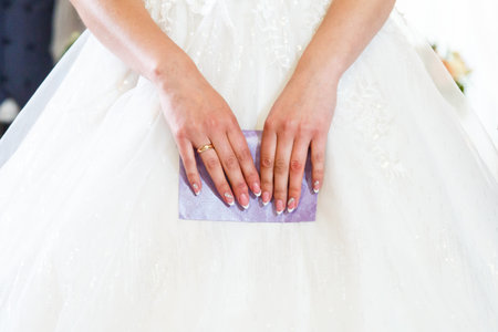 The bride holds a purple envelope in her hands, a French manicureの写真素材