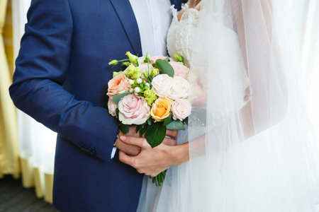Beautiful wedding bouquet of flowers in the hands of the newlywedsの写真素材