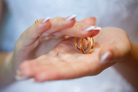 gold wedding rings in hands of newlyweds on wedding dayの写真素材