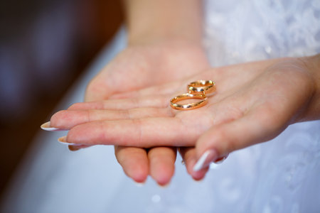 gold wedding rings in hands of newlyweds on wedding dayの写真素材