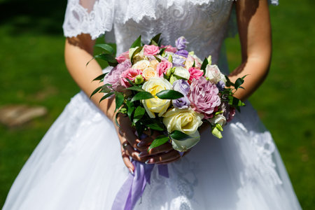 Beautiful wedding bouquet of flowers in the hands of the newlywedsの写真素材
