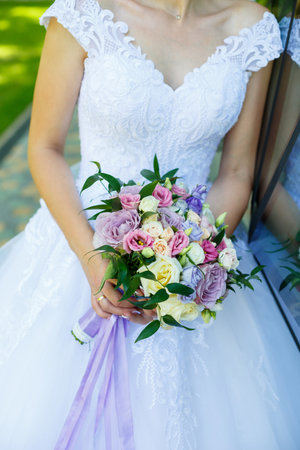 Beautiful wedding bouquet of flowers in the hands of the newlywedsの写真素材