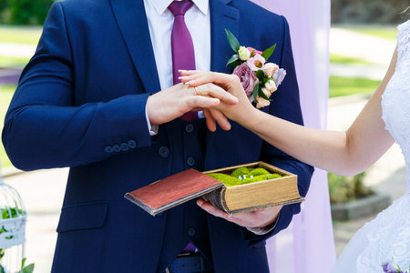 gold wedding rings in hands of newlyweds on wedding dayの写真素材