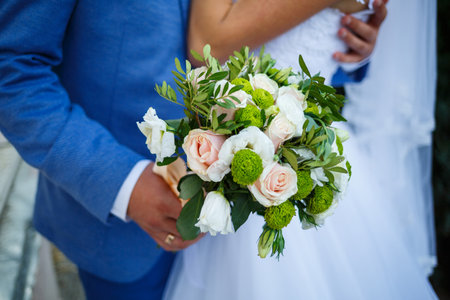 Beautiful wedding bouquet of flowers in the hands of the newlywedsの写真素材
