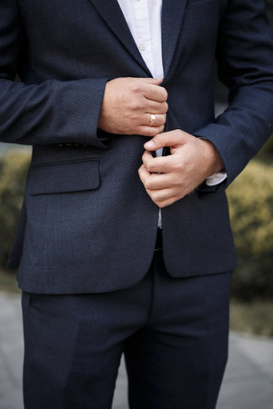 Stylish man groom buttoning a button on his jacketの写真素材