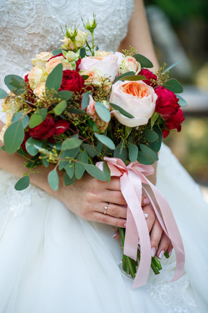Beautiful wedding bouquet of flowers in the hands of the newlywedsの写真素材