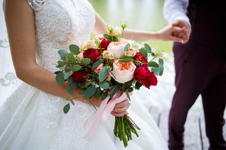 Beautiful wedding bouquet of flowers in the hands of the newlywedsの写真素材