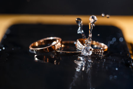 gold wedding rings for newlyweds on a wedding day on a black background with water drops. Jewelry