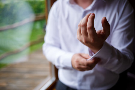 Man businessman buttoning a button on the sleeve of a white dress shirt