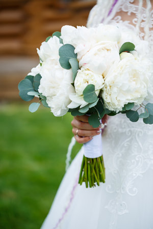 Beautiful bride holding a delicate bouquet of flowers in her hands on a wedding dayの写真素材