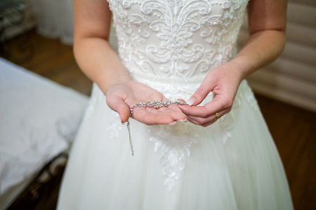 bride puts on wedding jewelry on the wedding dayの写真素材