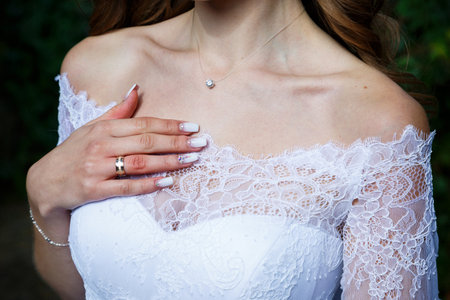Bride's hands folded on a white wedding dressの写真素材