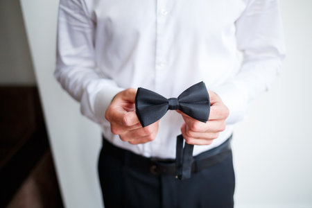 Young male businessman dressed in a white shirt with a short beard wears a black bow tieの写真素材