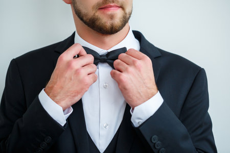 Stylish man groom puts a bow tie around his neckの写真素材