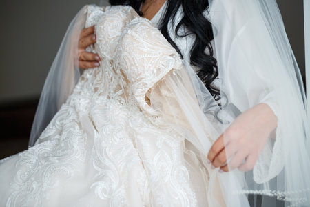 The bride holds a white dress in her hands on the wedding day.の写真素材
