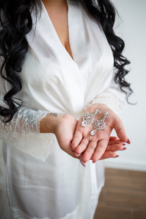 Beautiful precious earrings lie in the palm of the brideの写真素材