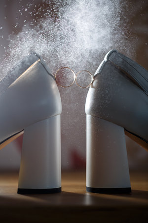Golden rings of the newlyweds between white shoes with heels. Precious rings of the bride and groomの写真素材