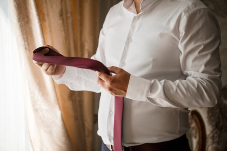 Young male businessman puts on a shirt and a stylish suit before a meetingの写真素材