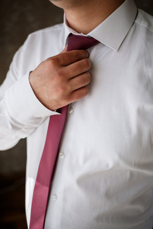 Young male businessman puts on a shirt and a stylish suit before a meetingの写真素材