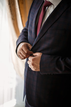 Stylish man groom buttoning a button on his jacketの写真素材