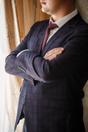 Stylish man groom buttoning a button on his jacketの写真素材