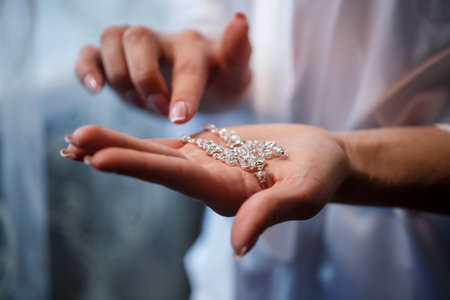 The bride holds earrings in her hand on her wedding day. Jewelry for a holiday for the newlywedsの写真素材