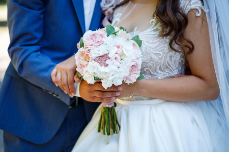 Beautiful wedding bouquet of flowers in the hands of the newlywedsの写真素材