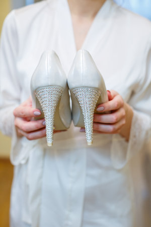 White shoes with heels in the hands of the brideの写真素材