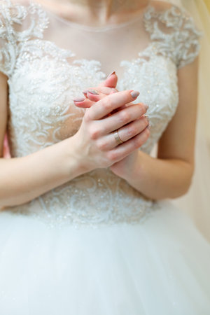 Bride's hands folded on a white wedding dressの写真素材