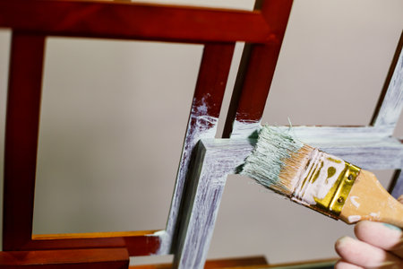 the master paints with a brush a wooden brown photo frame with light paintの写真素材