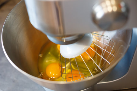 Beating eggs with sugar in a kitchen machine. Cream nozzleの写真素材