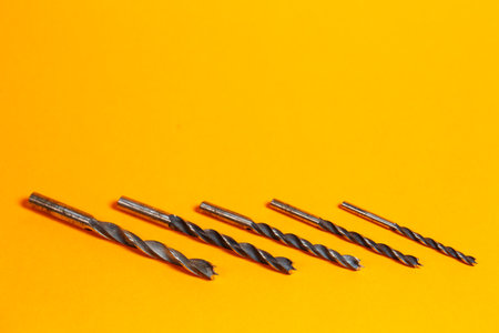 Drills for wood of different sizes for a drill on an orange background. Construction toolの写真素材