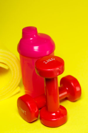 red dumbbells, pink shaker, yellow mat, colored background, sports, energy drink, gym equipmentの写真素材