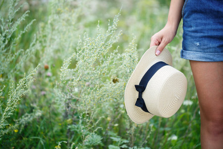 young beautiful girl in denim overalls and a light hat walking in the parkの写真素材