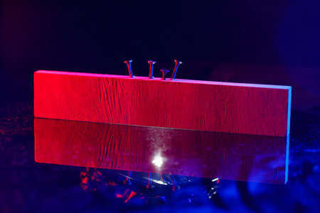 Screws screwed into a wooden beam in hard red lightの写真素材