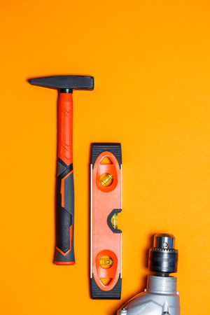 Tools for repairing home use. Hammer for nails, level and drill on an orange background. Toolkit for the wizardの写真素材