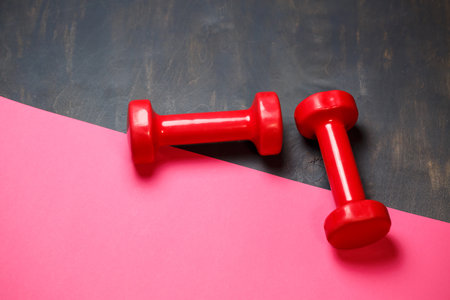 Conceptual fitness and healthy sport background with pink dumbbell on pink background. Flat lay top view with copy space.の写真素材