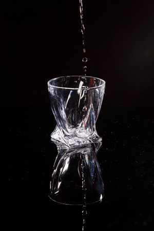 The black background is a scan in which water pours. Splashing water on glassの写真素材