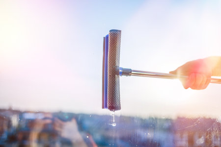 Window cleaning in high-rise buildings, houses with a brush. Window cleaning brush. Large window in a multi-storey building, cleaning service. Dust removal and glass washing.の写真素材