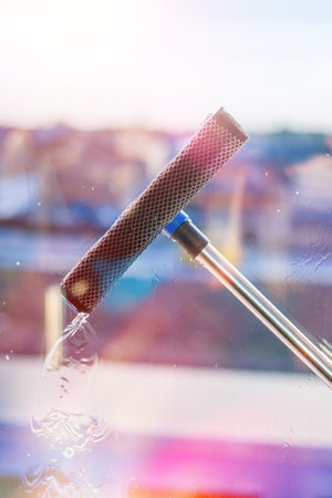 Window cleaning in high-rise buildings, houses with a brush. Window cleaning brush. Large window in...