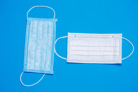 Blue and white medical surgical mask for protection against the virus on a colored background
