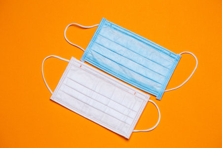 Blue and white medical surgical mask for protection against the virus on a colored background