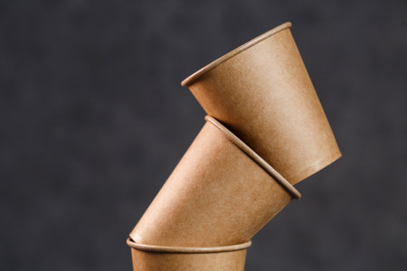 Disposable paper cups for drinks on a dark background. Cookware for picnic Eco. Empty coffee cup with youの写真素材